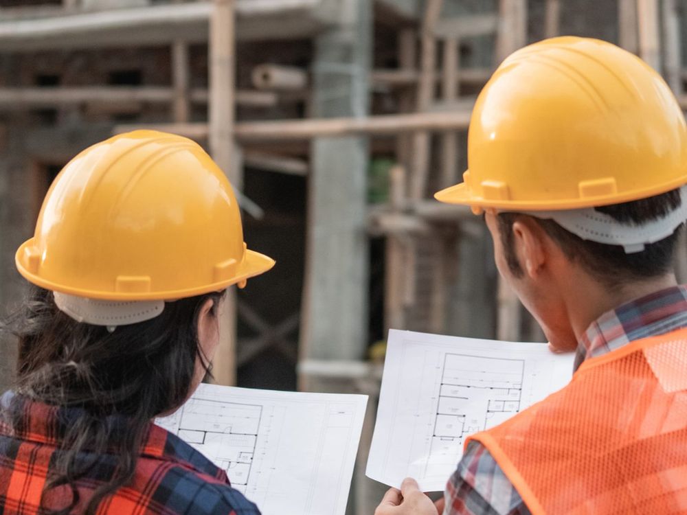Two Creek Ocean Construction workers in hard hats reviewing drawings on a job site